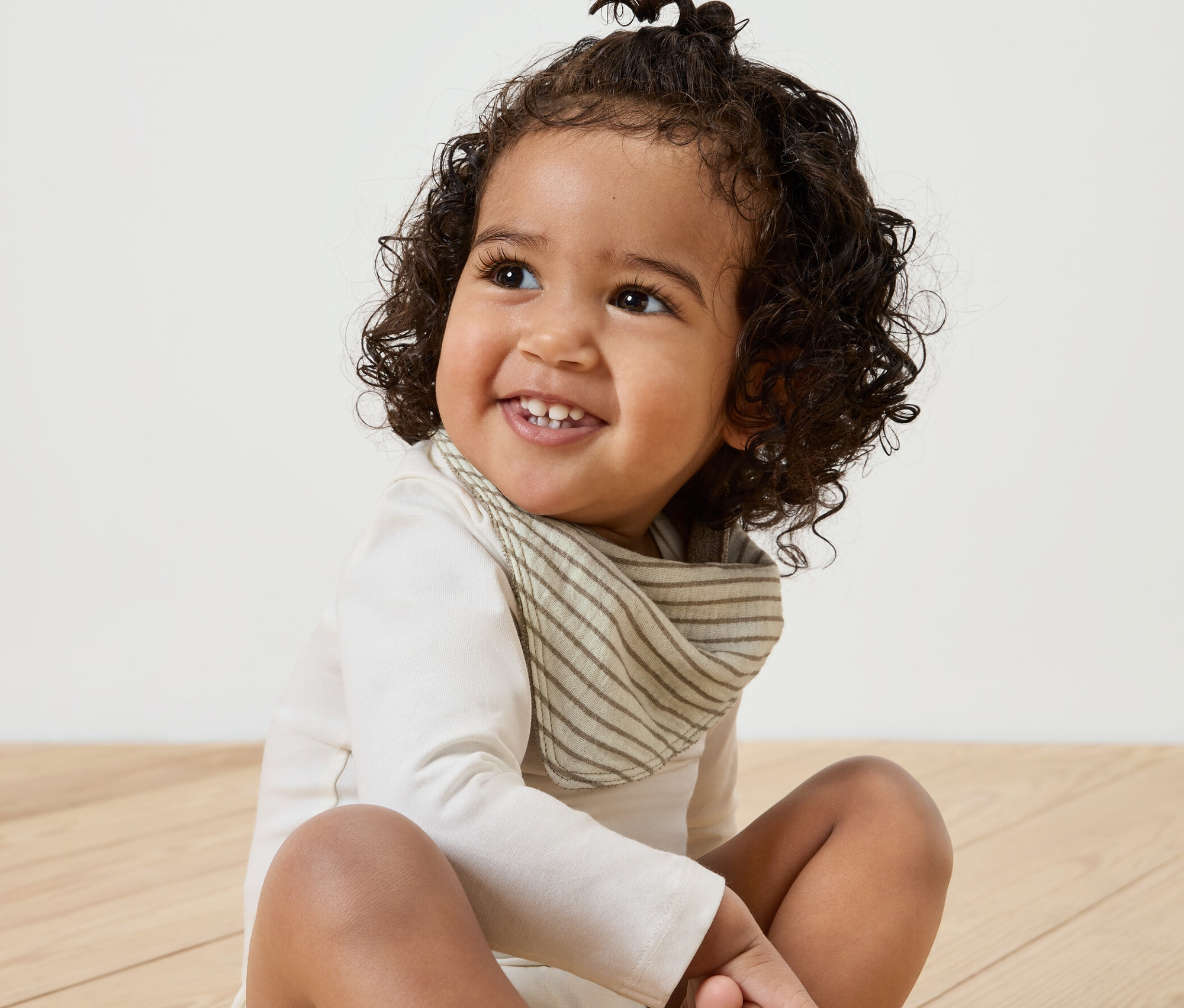 Usmievajúce sa dieťa sedí na drevenej podlahe a má na sebe detskú mušelínovú šatku na krk, 5 ks.