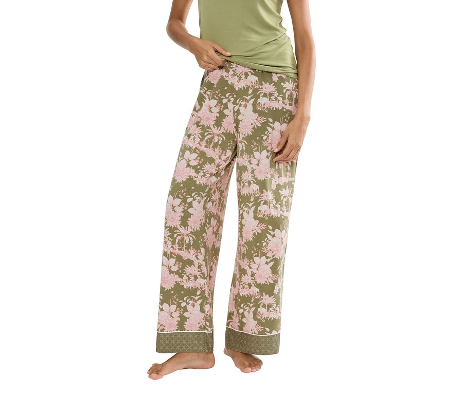 Žena má na sebe zelený tielko a olivovozelené pyžamové nohavice s ružovými kvetmi.