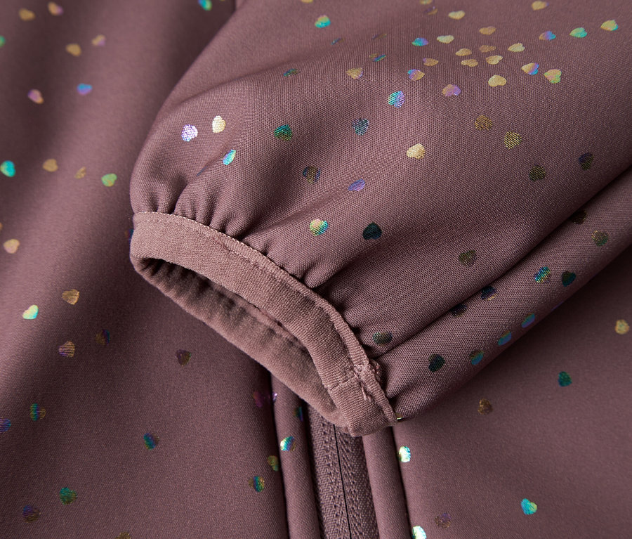 Detail záberu rukávu a zipsu fialovej softshellovej bundy s farebnými srdiečkami.