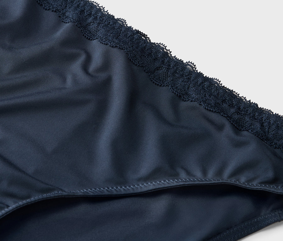 Detailný záber na tmavomodré dámske nohavičky s čipkovaným lemom.