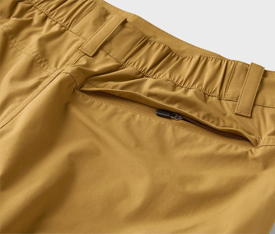 Detailný záber khaki nohavíc s elastickým pásom a vreckom na zips.