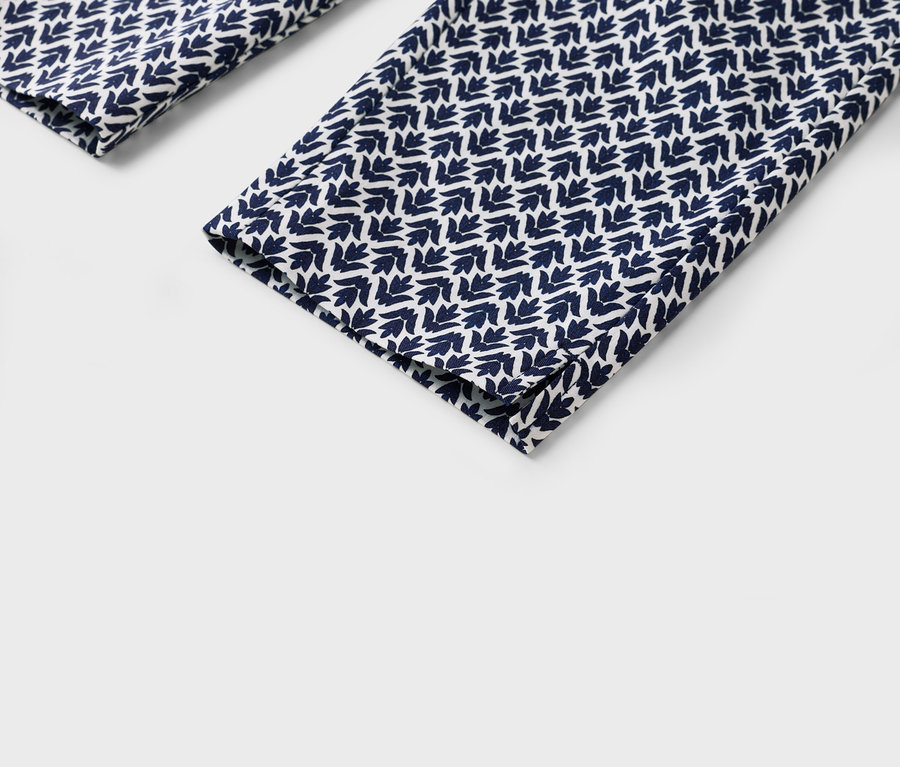 Detail záberu nohavíc s modro-bielym listovým vzorom.