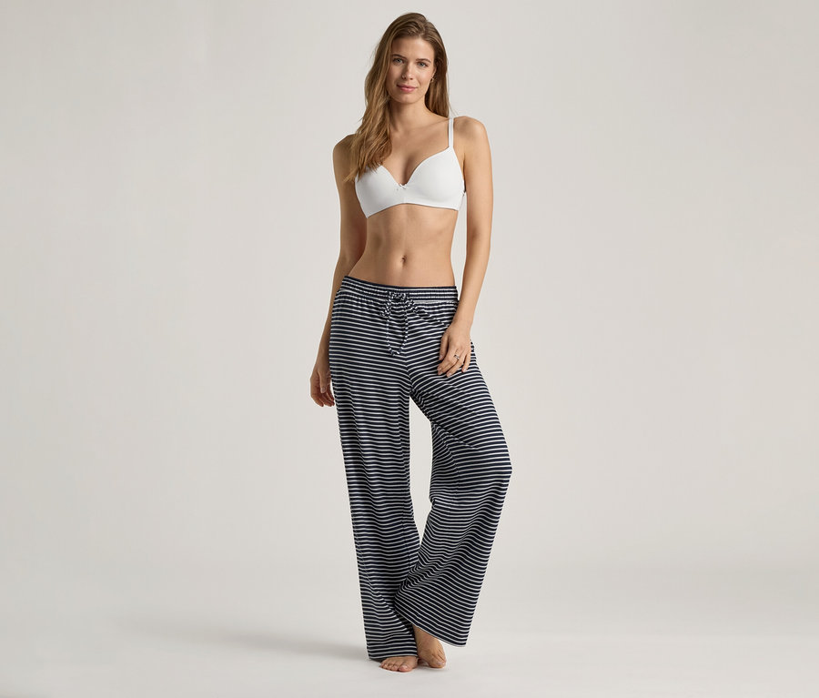 Žena má na sebe bielu podprsenku s mäkkými košíčkami a modro-biele pruhované nohavice.