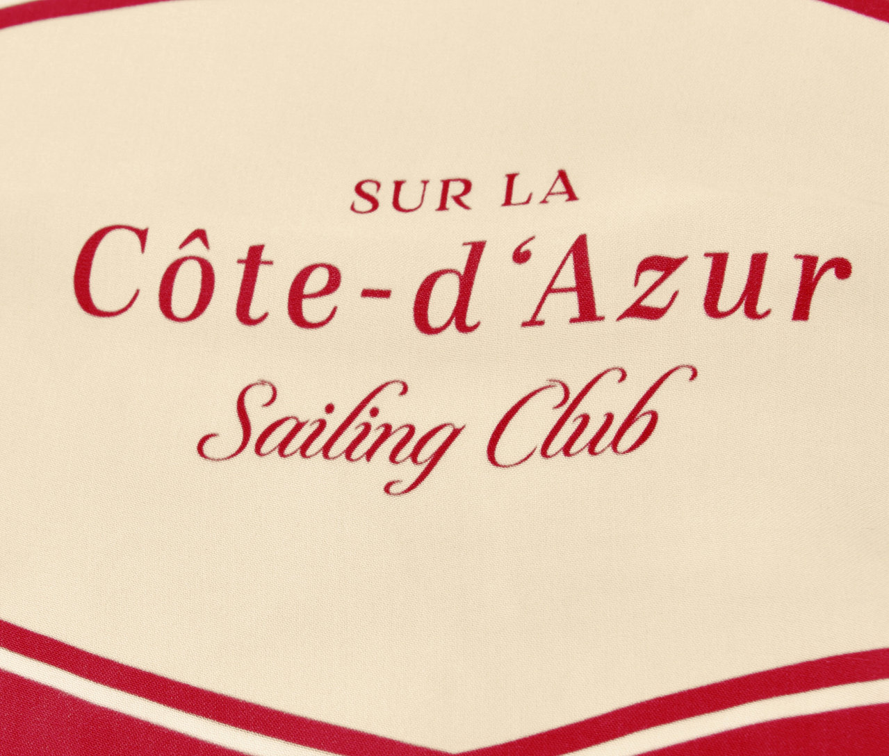 Detail záberu šatky na krk Street One »Nicki« s červeným nápisom „Côte-d'Azur Sailing Club“ na béžovom pozadí.