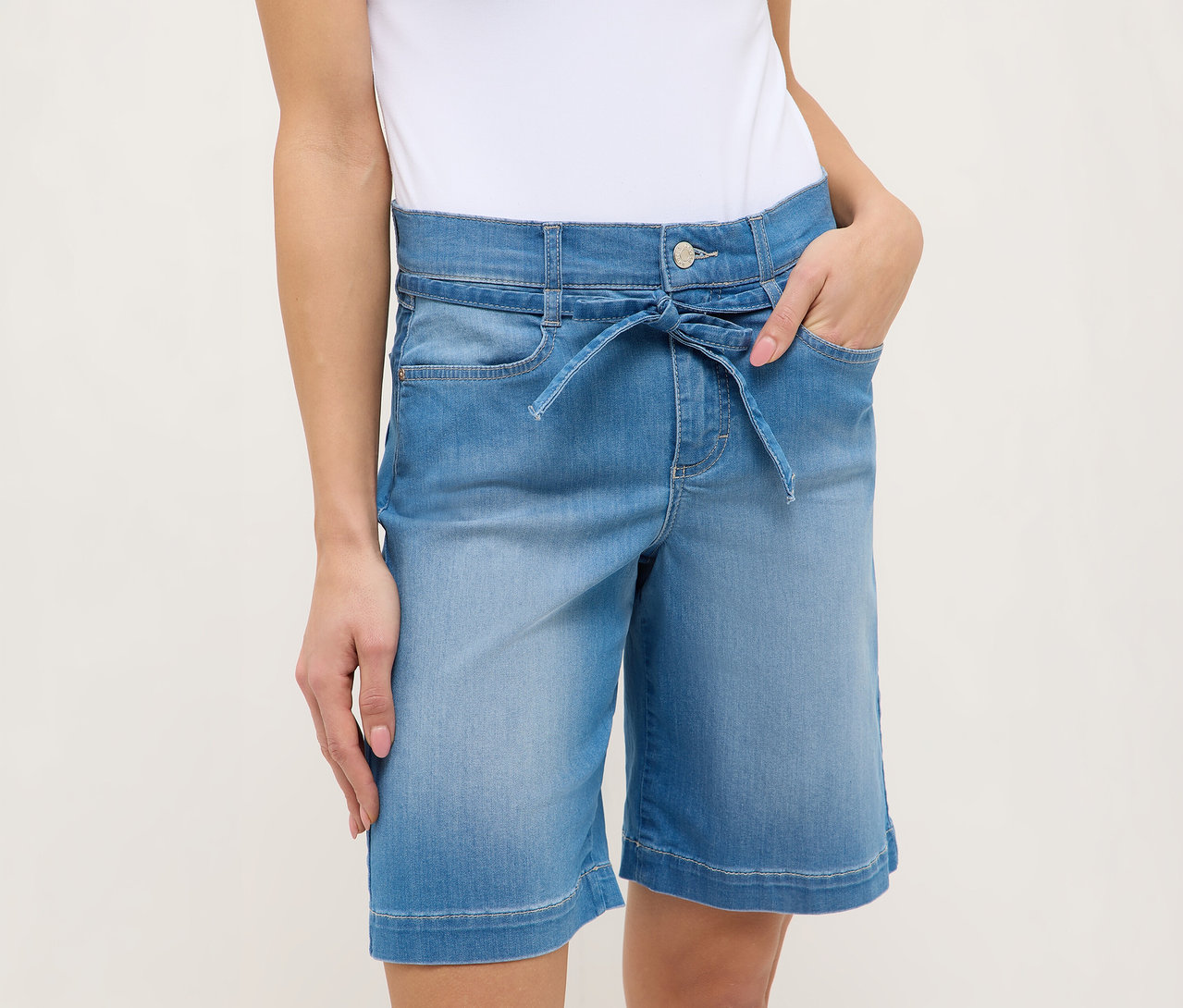 Žena v svetlomodrých šortkách Angels Denim »Lia City« so zaväzovacím opaskom a rukami vo vreckách.