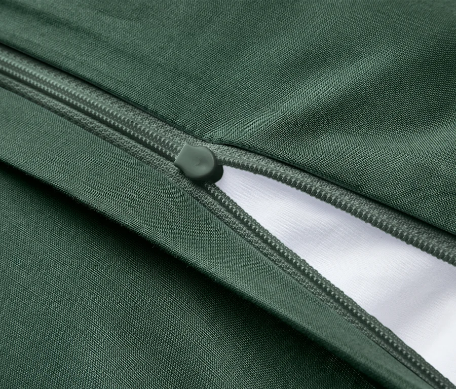 Tmavozelená látka s čiastočne otvoreným tmavozeleným zipsom, odhaľujúcim biely materiál pod ním.