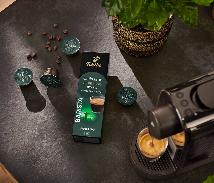 Espresso kávovar plní šálku. V pozadí je balenie kapsúl Espresso Brasil – 10 kapsúl a kávové zrno.