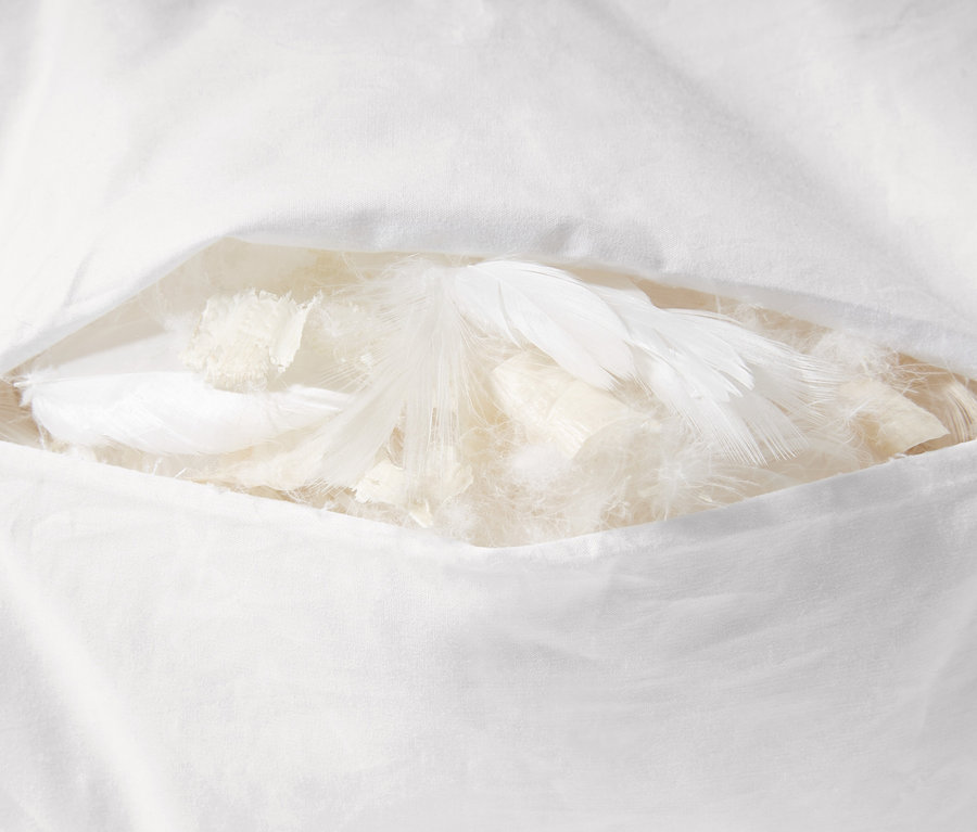 Detail bieleho vankúša s výplňou z borovice limbovej, čiastočne otvoreného, odhaľujúceho perie a výplň.