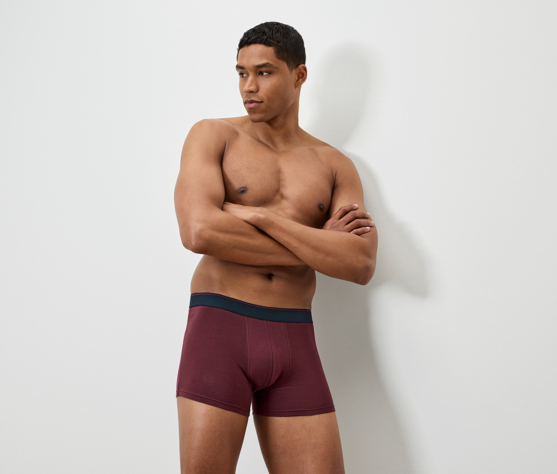 Muž so skríženými rukami má na sebe bordové boxerky.