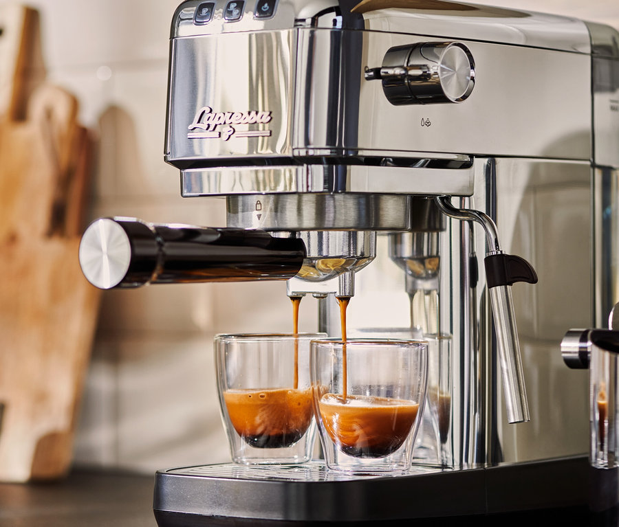 Strieborný pákový kávovar »Lapressa« pripravuje espresso do dvoch sklenených šálok.