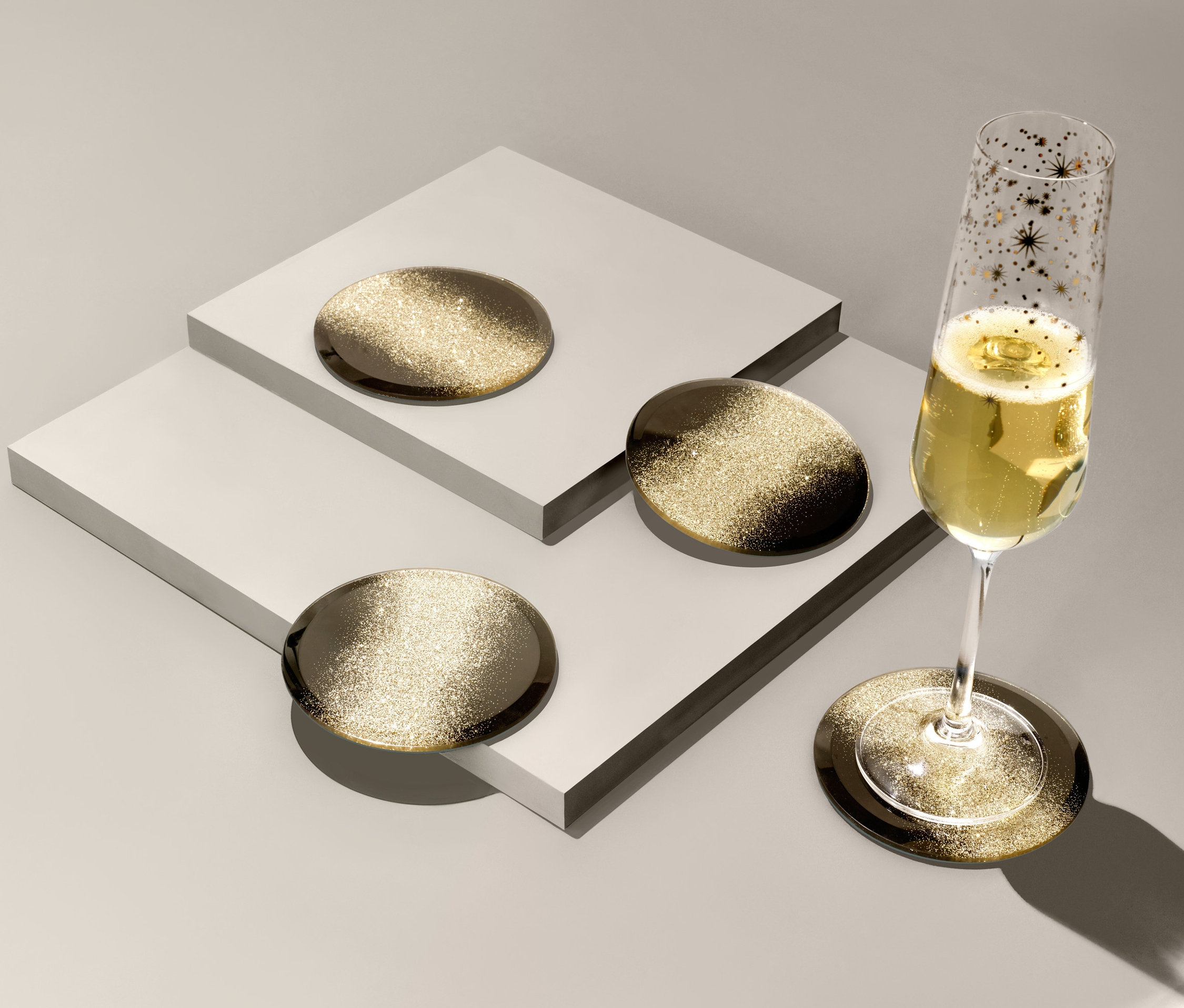 Pohár šampanského stojí na jednej zo 4 sklenených podložiek s trblietavým efektom.