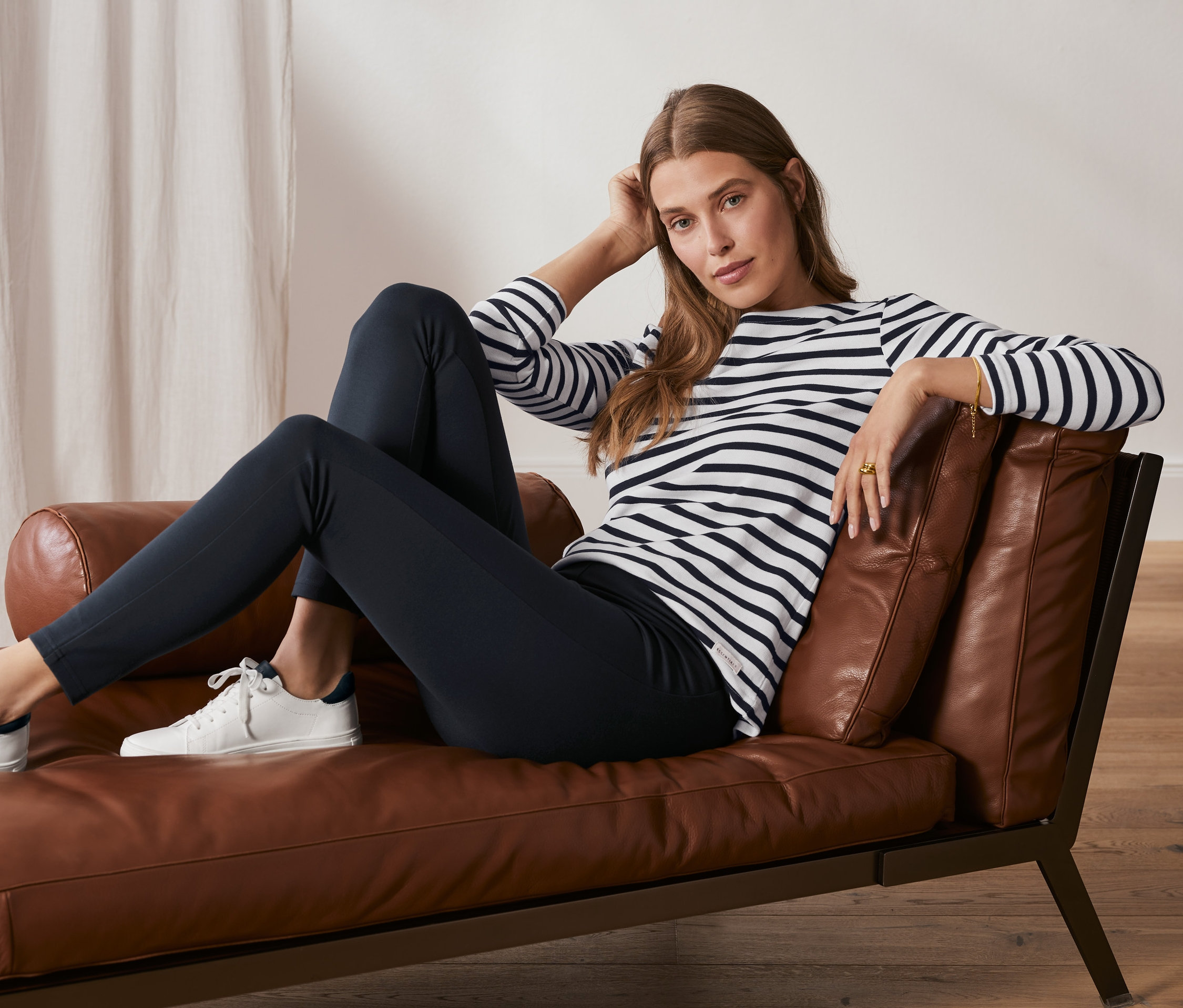 Žena sedí na koženom kresle a má na sebe tmavomodré jednoduché legínsy z džerseja Heavy Jersey.