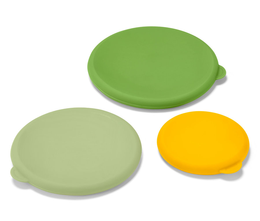 Tri silikónové veká na udržiavanie čerstvosti, zelené, svetlozelené a žlté, ležia na bielom povrchu.