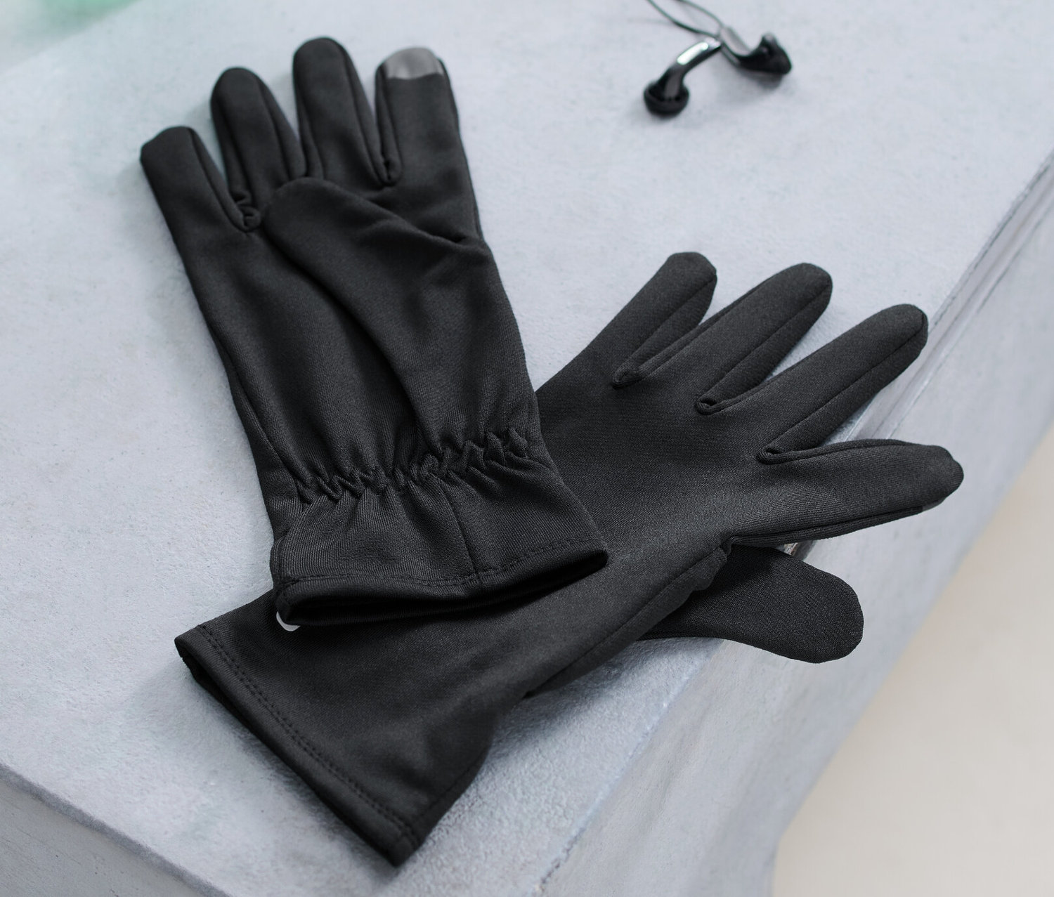 Na lavici ležia bežecké rukavice, fľaša s vodou a slúchadlá.