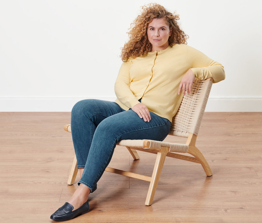 Žena sedí v kresle a má na sebe tregínsy »Fit Nelly« a kardigán z jemného úpletu.