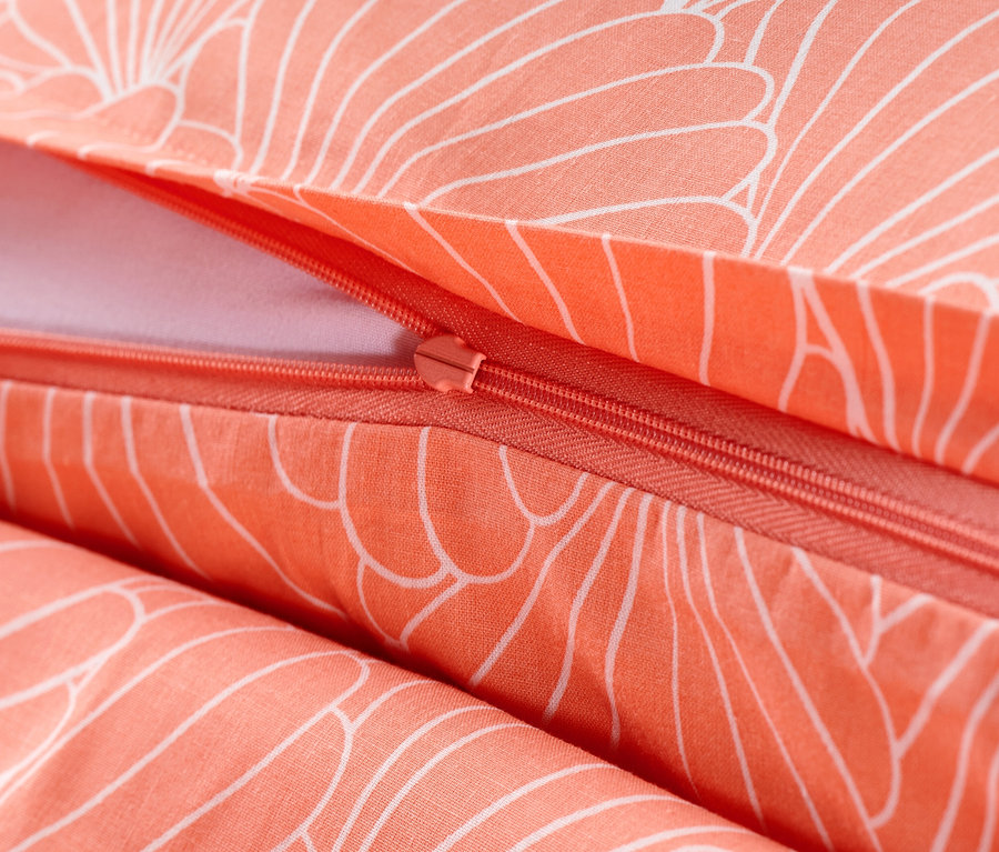 Detail lososovej posteľnej bielizne renforcé so zipsom a bielym kvetinovým vzorom.