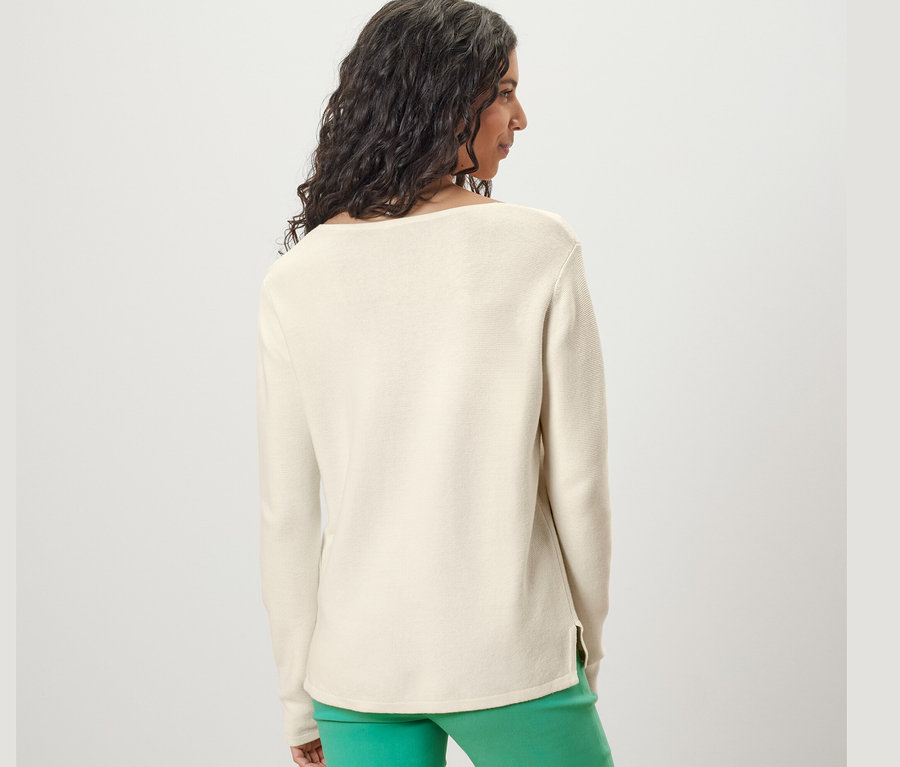 Žena zozadu nosí krémovobiely pletený pulóver.