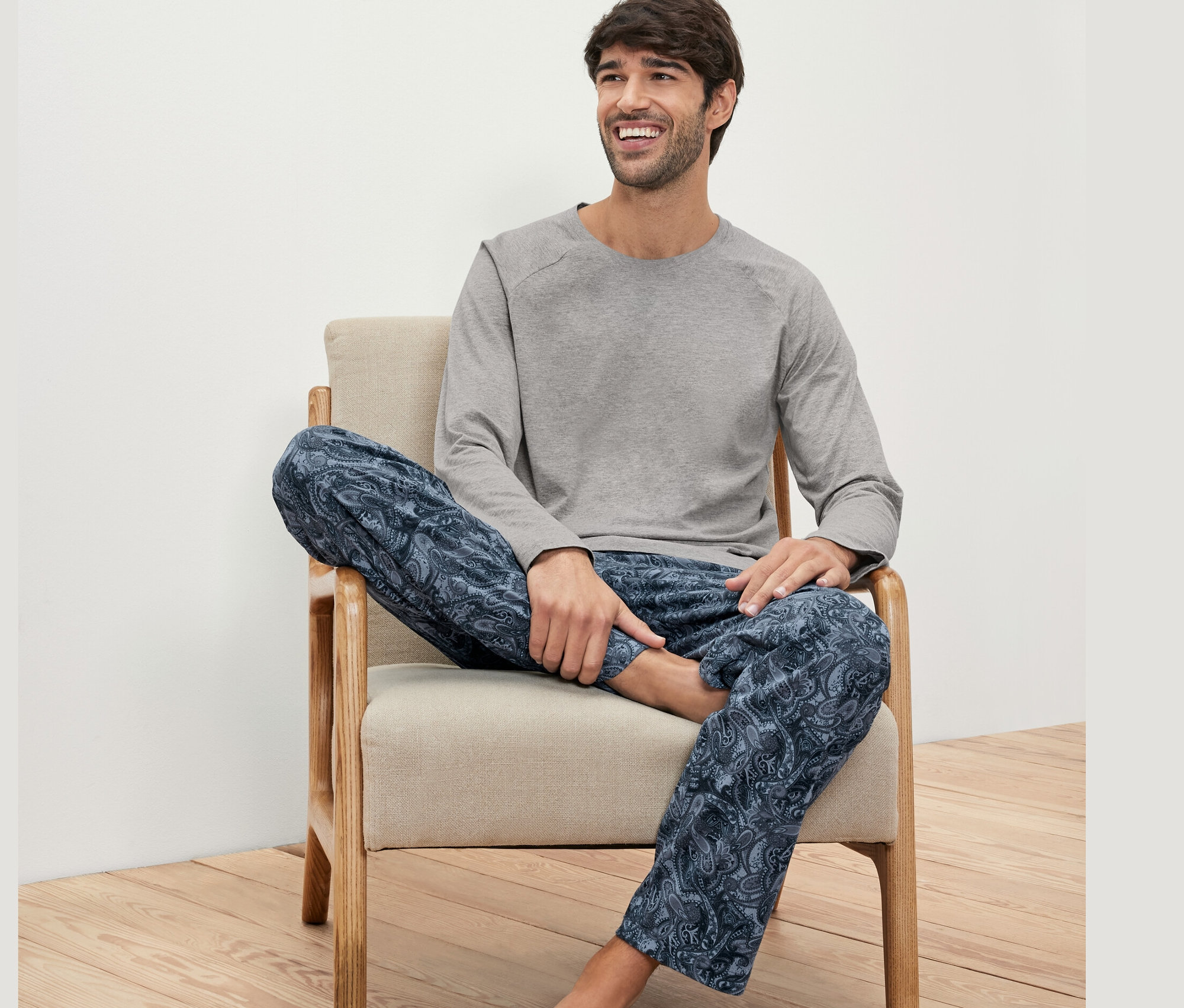 Muž sedí v kresle a má na sebe pyžamovú súpravu.