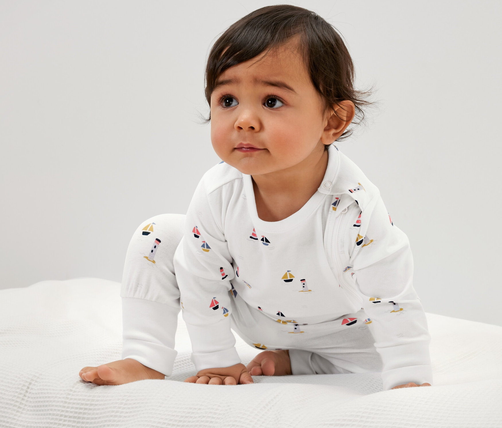 Dieťa v bielom pyžame s námorníckym vzorom, 3 ks, sedí na bielej textúrovanej podložke.