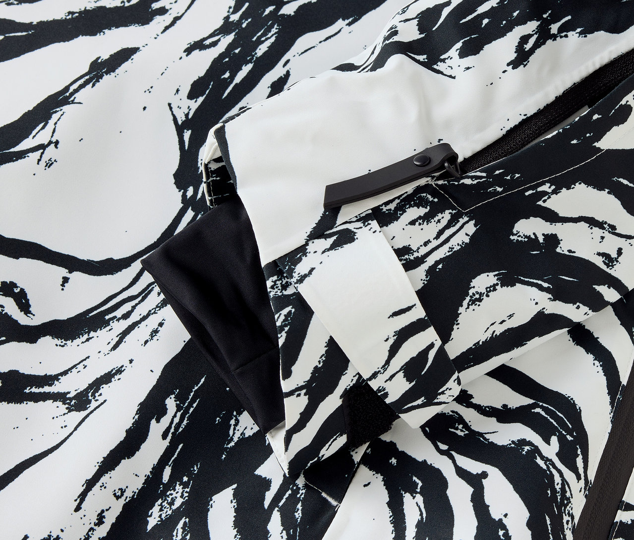 Detail bundy so vzorom zebry v bielej a čiernej farbe, viditeľný rukáv a zips.