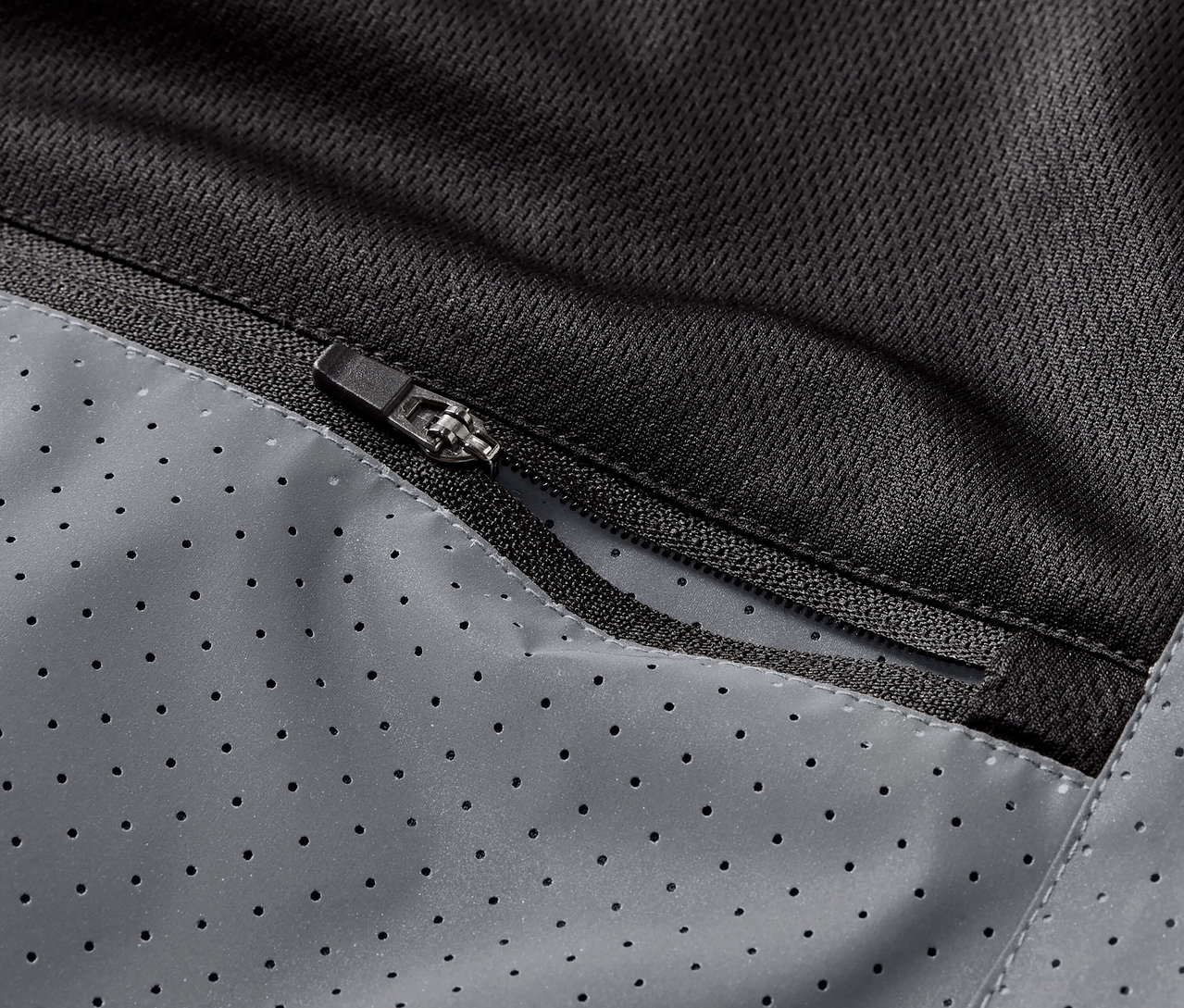 Detailný záber na vrecko na zips na reflexnej bežeckej veste.