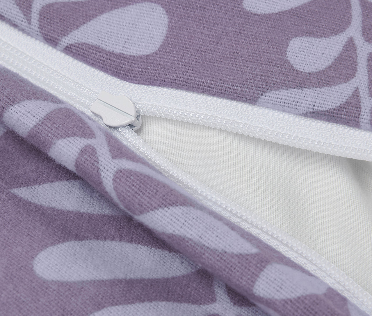 Detail fialovej obliečky na vankúš s bielymi listami a zipsom.