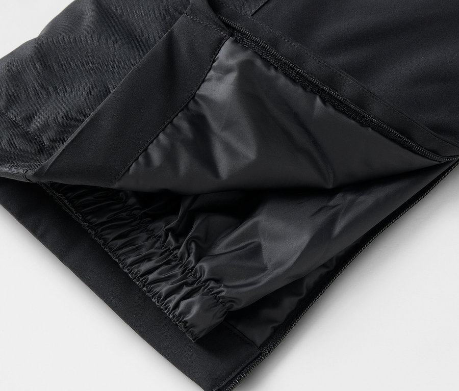Detail čiernych nohavíc s rozopnutým zipsom a vnútornou vrstvou.