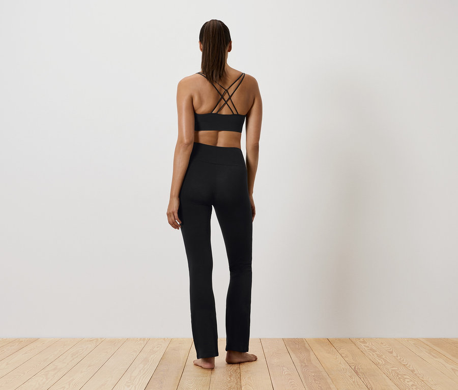 Žena v čiernom športovom oblečení, chrbtom k fotoaparátu.