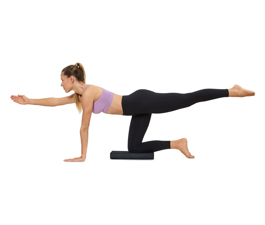 Žena cvičí jogu na podložke, má na sebe športové oblečenie.