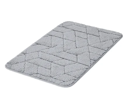 Na bielom pozadí leží sivý koberec s geometrickým vzorom.