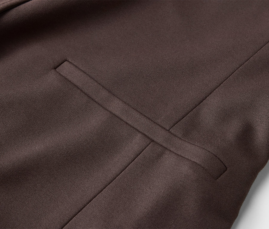Detail hnedastej vesty s naznačeným vreckom.