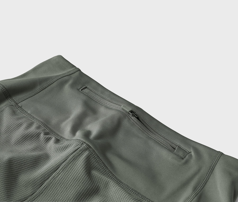 Detailný záber olivovozelených nohavíc s vreckom na zips.