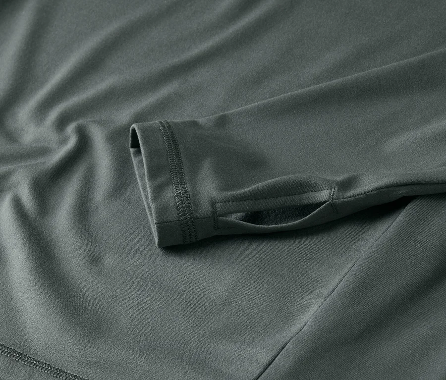 Detail šedej košeľe s dlhým rukávom a otvorom na palec.