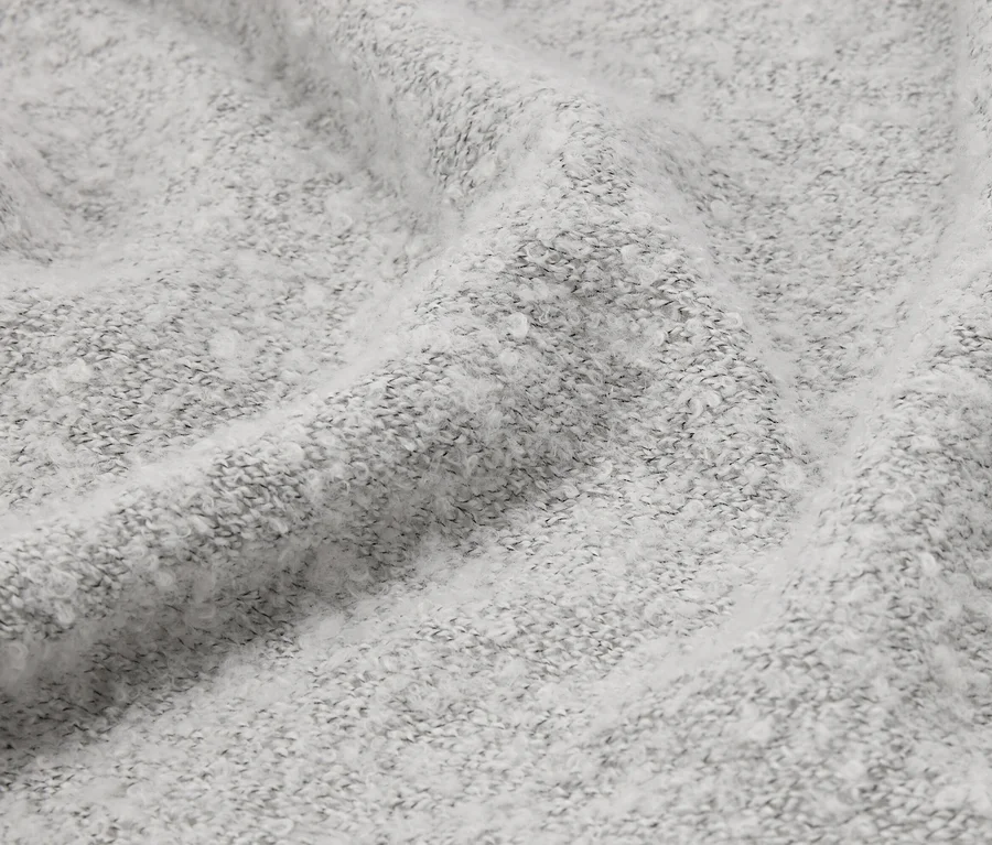 Detail záberu pokrčenej, svetlosivej látky s nadýchanou textúrou.
