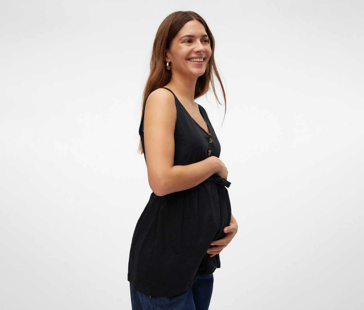 Usmievavá sa žena drží brucho a má na sebe čierny štýlový top MAMALICIOUS »MLEVI LIA« a džínsy.