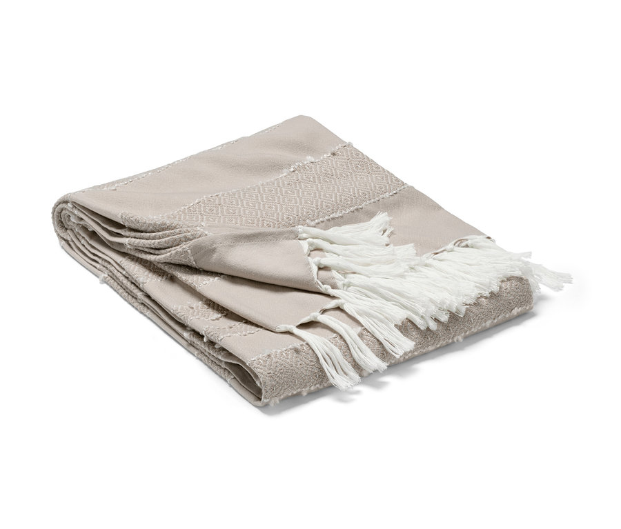 Béžová deka s ozdobnými strapcami je zložená.