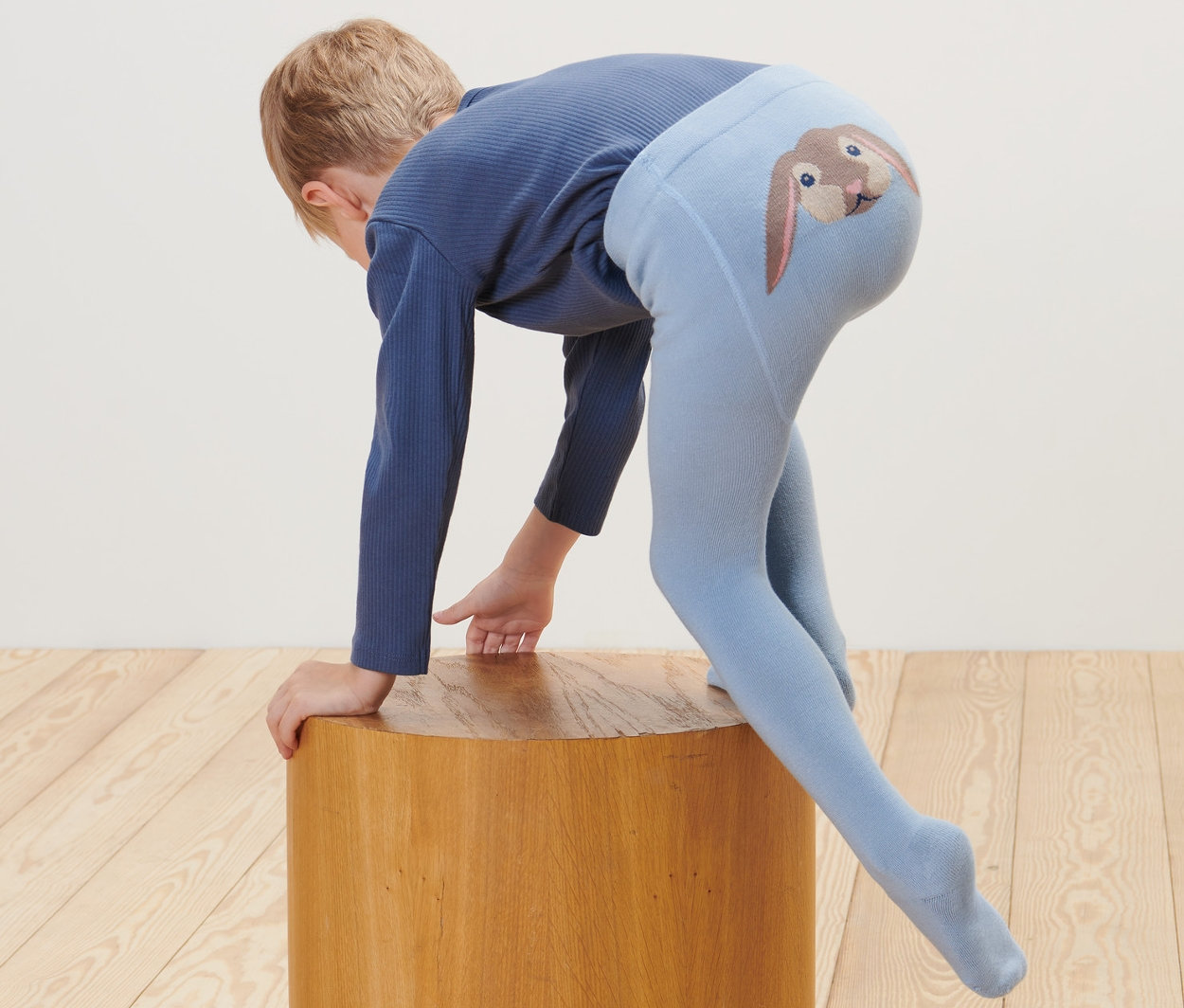 Dieťa sa opiera o drevenú stoličku a má na sebe modré pančuchy s obrázkom králika na zadku. Na zemi leží plyšová hračka. Dojčenské a detské pančuchy, 2 ks.