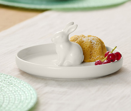 Tanier s veľkonočným zajačikom, bábovka a červené ríbezle na stole.