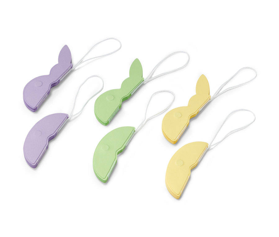 Šesť papierových veľkonočných ozdôb Papierové veľkonočné ozdoby, 6 ks, fialovej, zelenej a žltej farby, ležia na bielom povrchu.