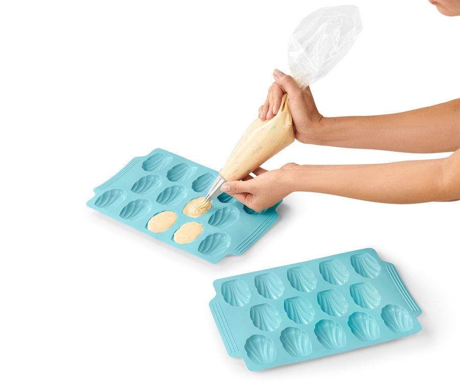 Žena plní cesto do modrej formy na pečenie madleniek, 2 ks.