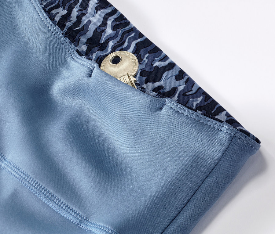 Detail modrých/svetlomodrých obojstranných športových legín s kľúčom vo vrecku.