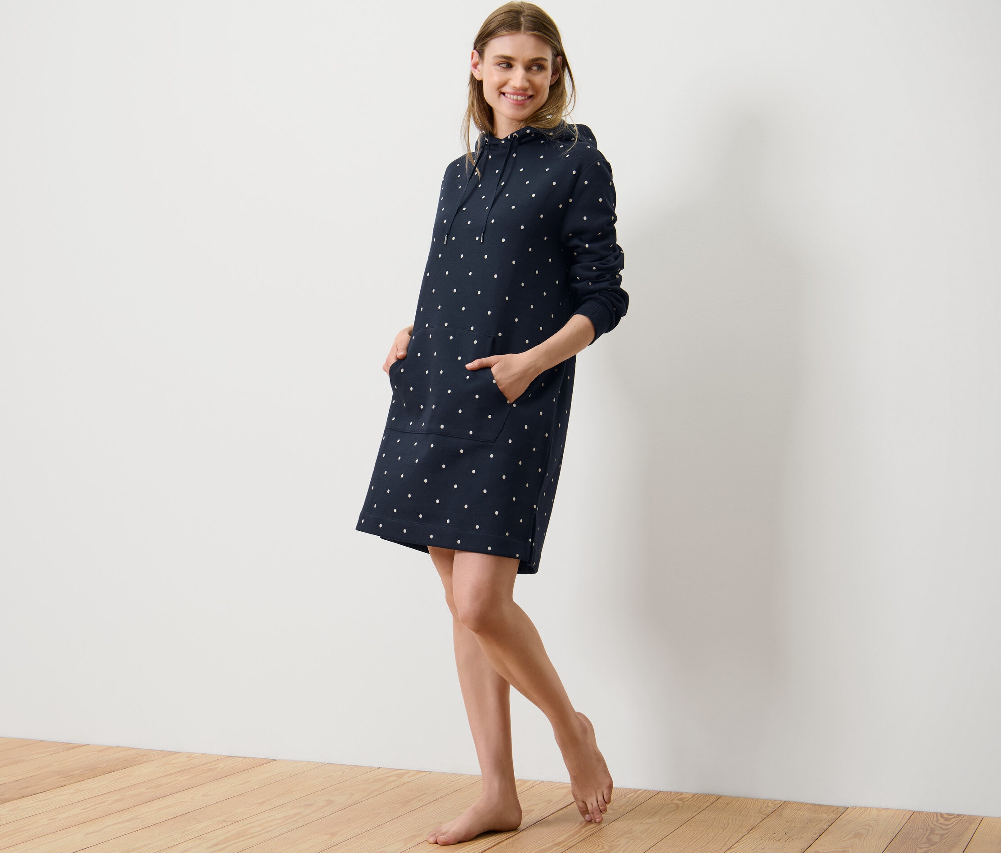 Žena pózuje vo voľnočasových šatách s bodkami.