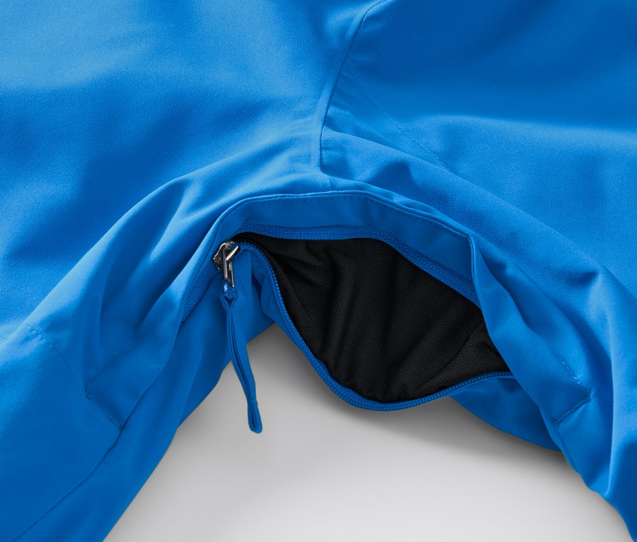 Detail modrej high-tech lyžiarskej bundy s rozopnutým vreckom.