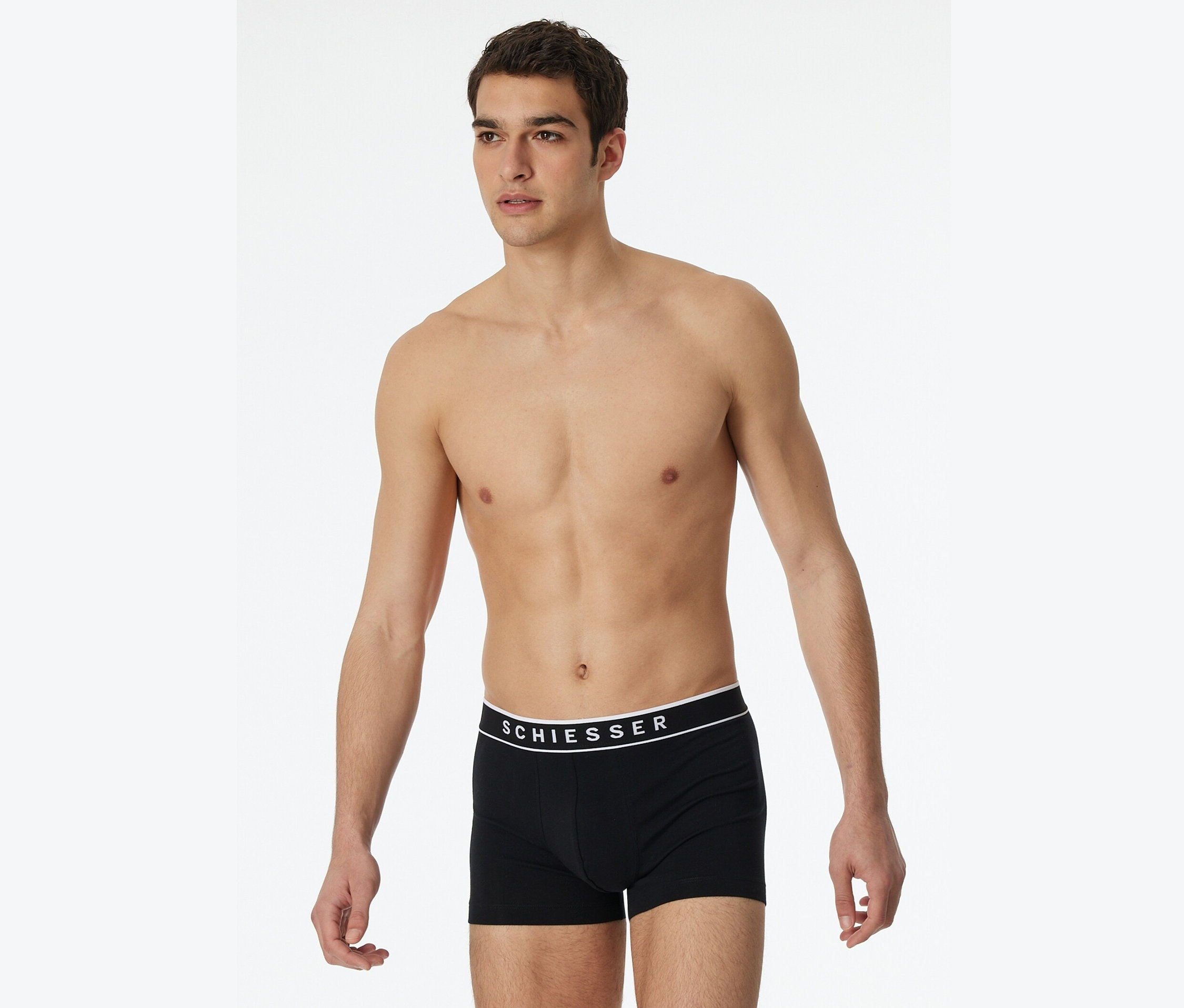 Muž pózuje bez trička v čiernych boxerkách Schiesser.