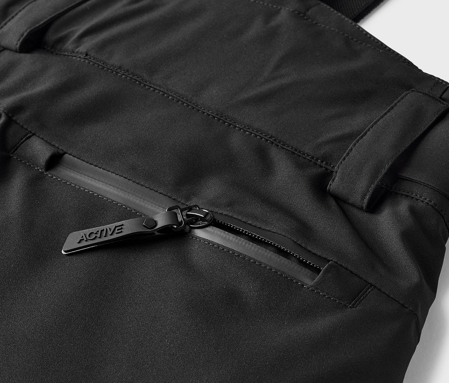 Detail čiernych nohavíc s vreckom na zips s jazdcom s nápisom ACTIVE.