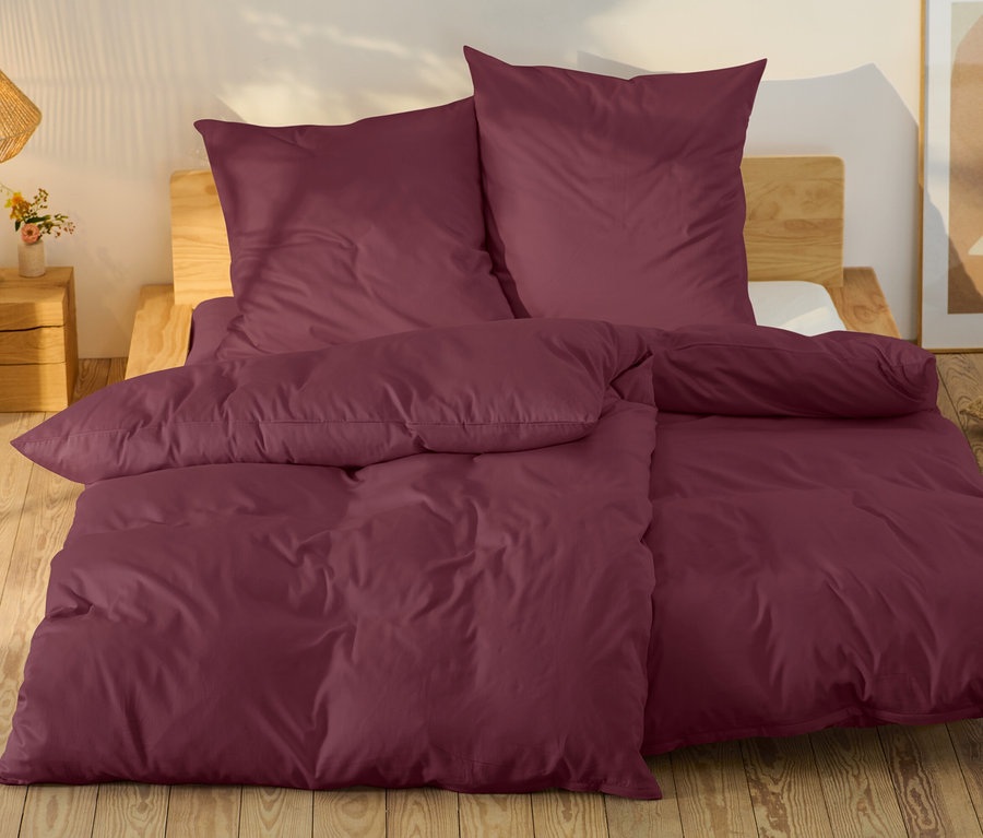 Vínová posteľná bielizeň na posteli s dreveným rámom.