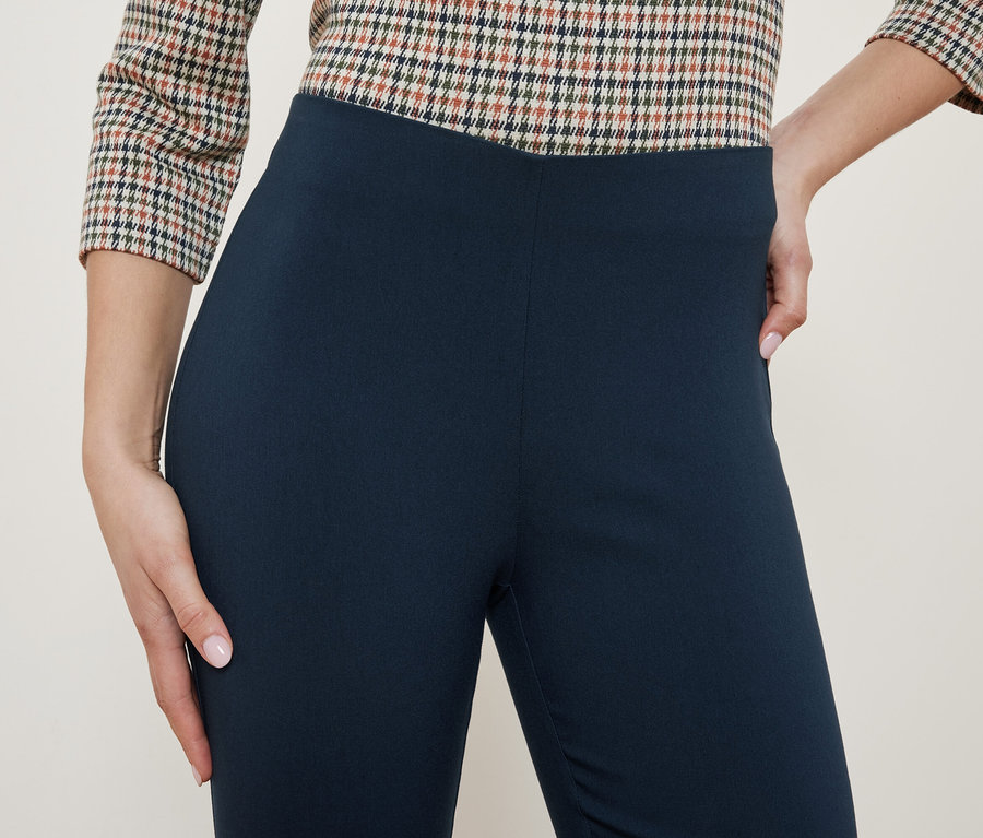 Vrchná časť dámskeho outfitu s kockovanou blúzkou a tmavomodrými legínami.