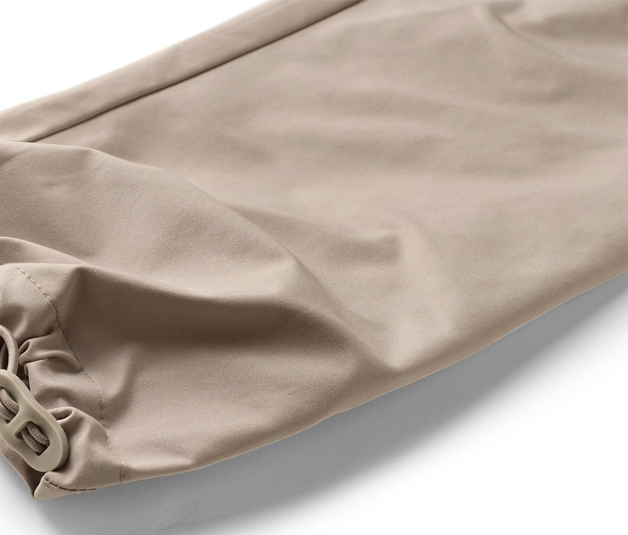 Detailný záber na spodnú časť béžových nohavíc s elastickým pásom a zarážkou na šnúrke.