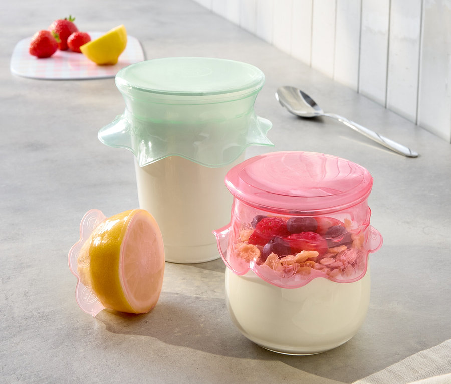 Na kuchynskej linke stoja dva poháre s jogurtom s ružovými a mätovými vrchnákmi a polovica citróna s ružovým vrchnákom.