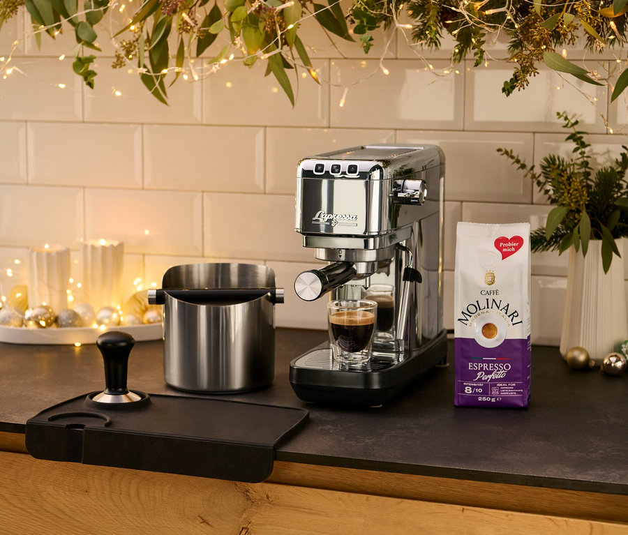 Na kuchynskej linke stojí strieborný pákový kávovar »Lapressa« vedľa šálky espressa.